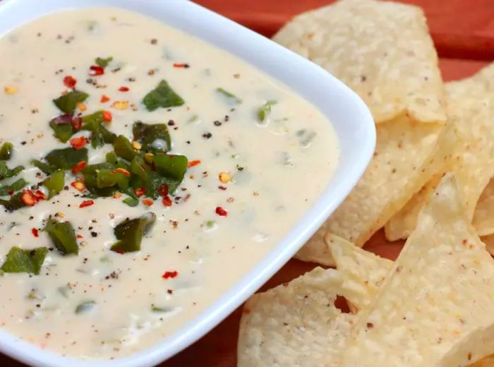 A creamy white cheese dip topped with finely chopped roasted poblano peppers