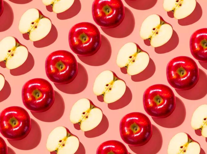 Apples arranged in a diagonal pattern on a pink background.