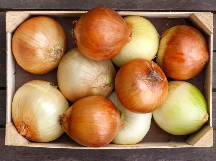 Overhead view of a wooden box filled with onions