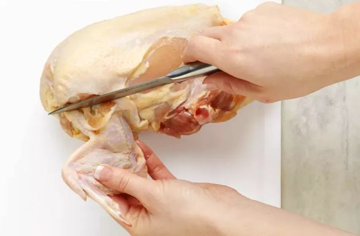 Cut through the joint where the wing connects to the body to detach it from the chicken carcass.