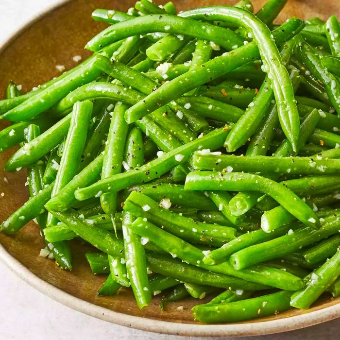 A close-up view of a bowl filled with creamy garlic butter green beans