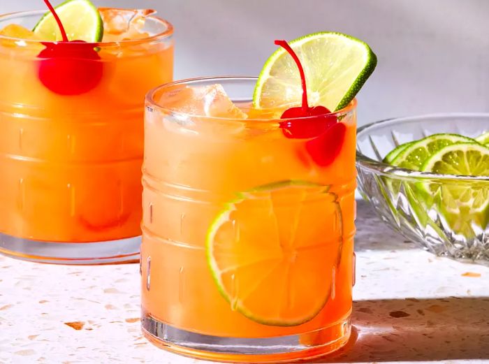 Close-up shot of two Mai Tai glasses, garnished with lime slices and cherries