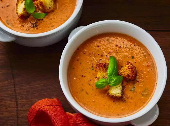 A close-up view of two bowls filled with rich and creamy tomato basil soup, ready to be enjoyed.