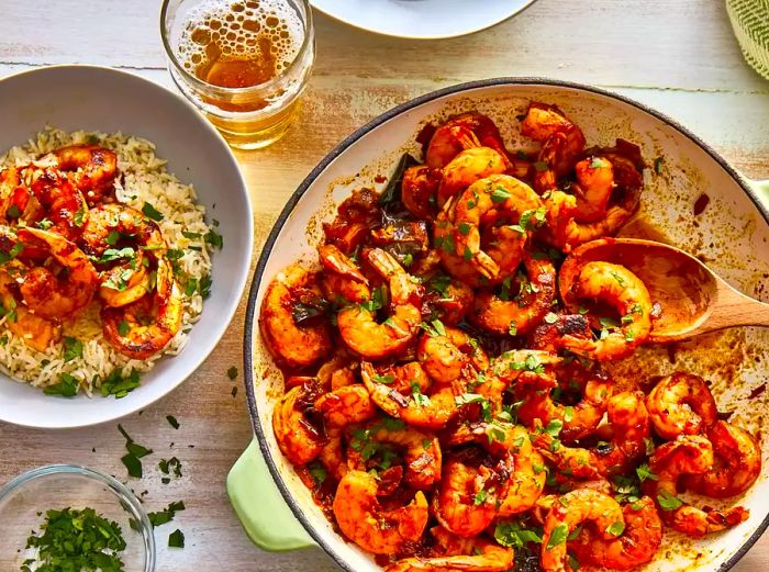 Close-up shot of Shrimp Curry in a pan with a wooden spoon, and Shrimp Curry served over rice in a bowl