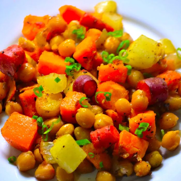 A close-up of perfectly roasted chickpeas and colorful vegetables on a sheet pan.