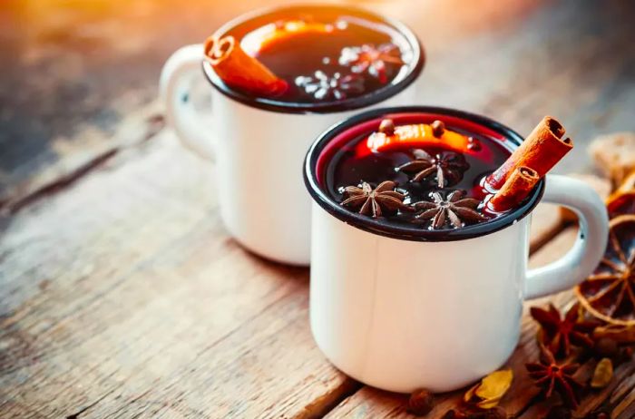 Mulled wine served in rustic white mugs with a mix of spices and citrus