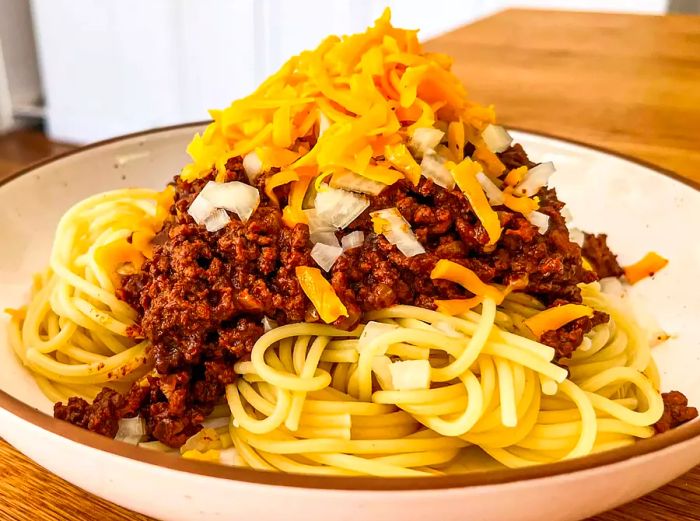 A close-up shot of Cincinnati-style chili served over a bed of spaghetti noodles.