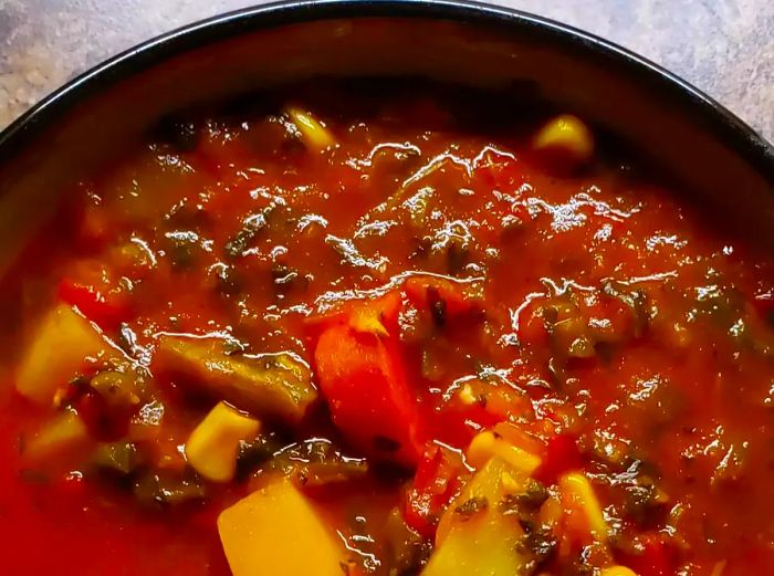 A close-up shot of a rich, chunky vegetarian vegetable soup simmering in a pot