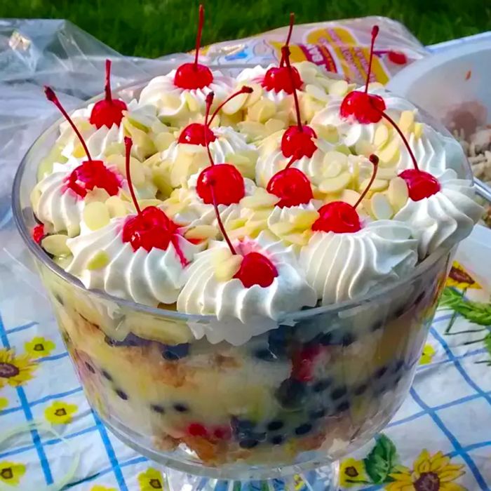 Close-up view of an English Trifle, garnished with cream, cherries, and nuts, served in a trifle bowl.