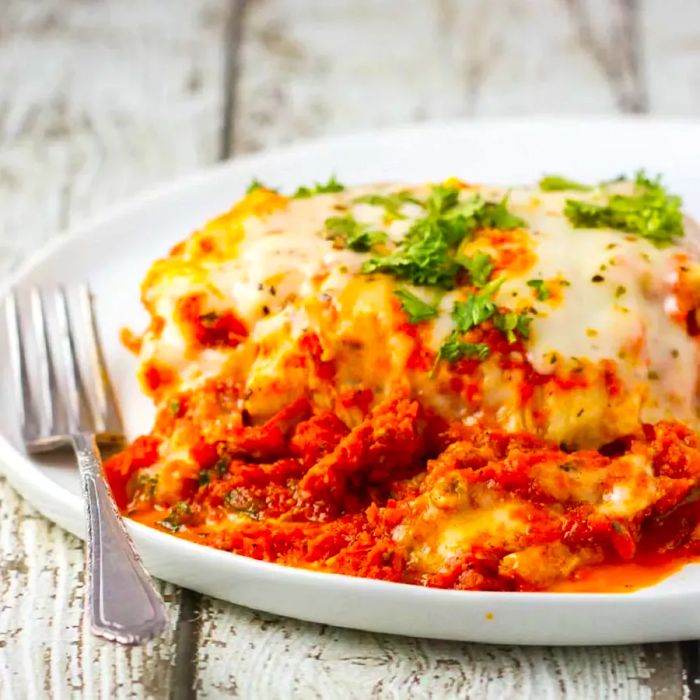 A serving of the World's Best Lasagna on a white plate with a fork