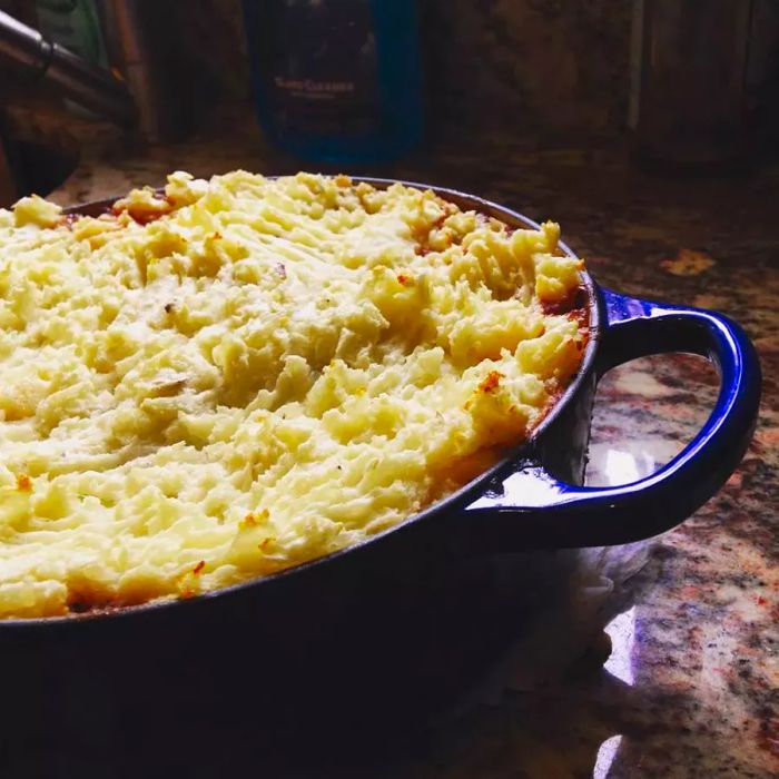 A beautiful dish of Sophie’s Shepherd’s Pie served in a blue Dutch oven.