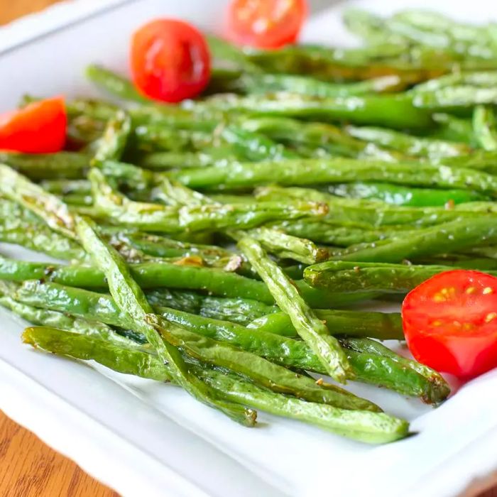 Roasted Green Beans with tomatoes served on a white plate