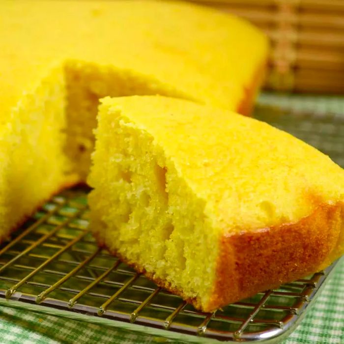 Cornbread cooling on a rack, with a wedge cut in the foreground