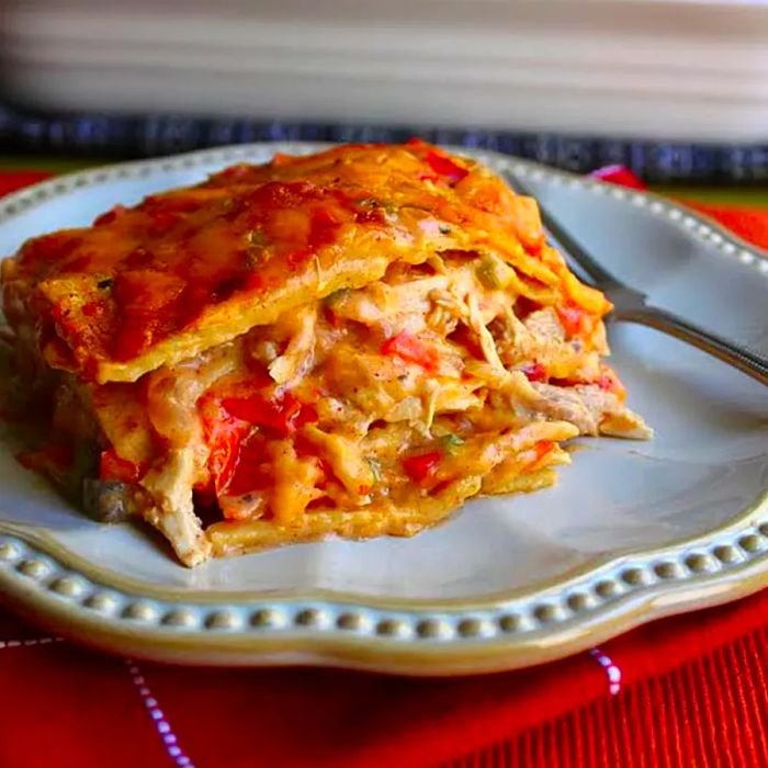 A hearty portion of casserole stacked between layers of corn tortillas, served on a white plate