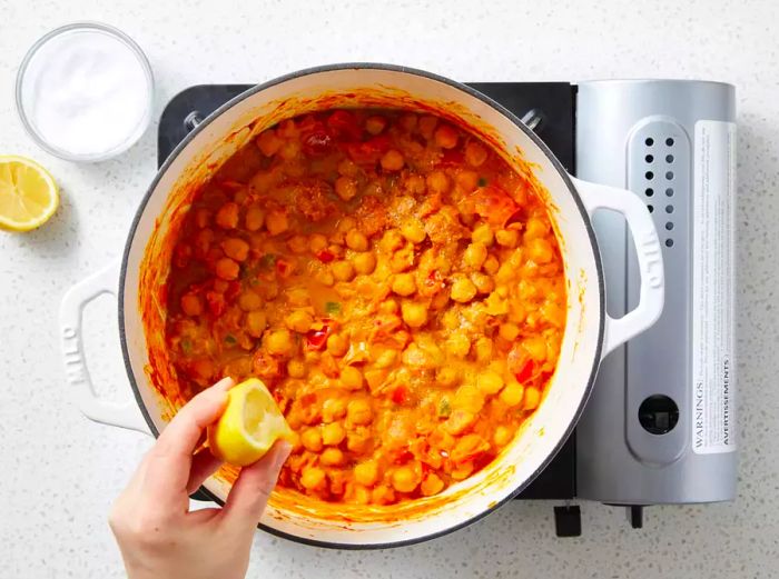 A half lemon is being squeezed into the pot.