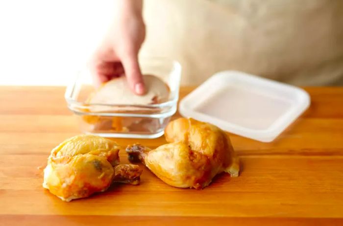 person placing cooked chicken in glass container