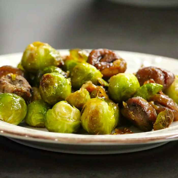 A close-up view of a plate filled with praline chestnuts and Brussels sprouts, taken from a low angle