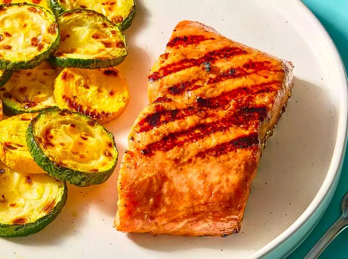 A plate of perfectly grilled salmon paired with roasted zucchini.