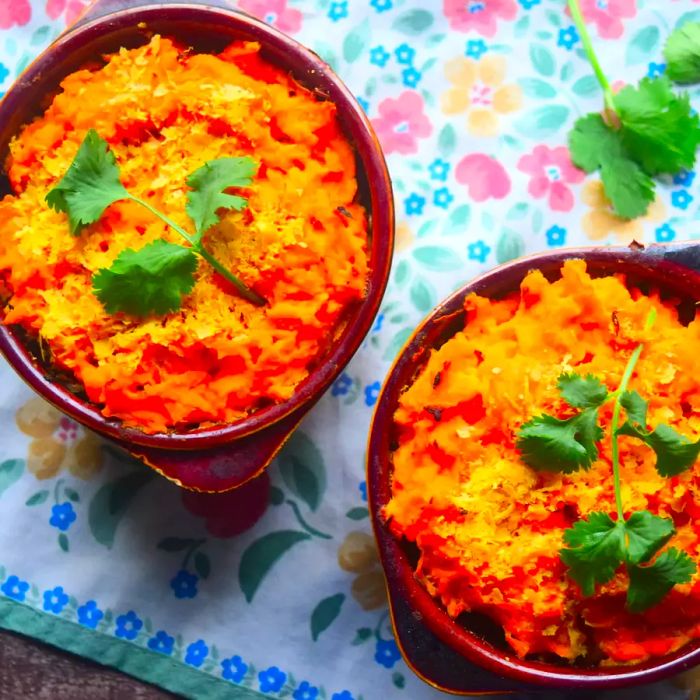 Two servings of Vegan Shepherd's Pie with Sweet Potato on a floral tablecloth.