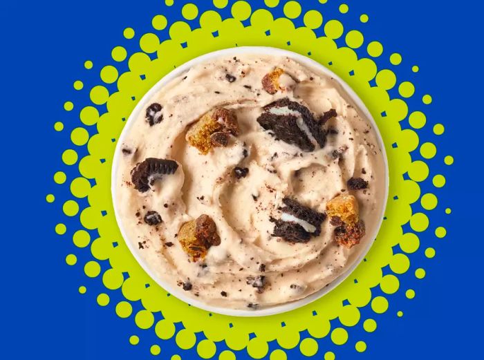 A top-down view of a Blizzard featuring Oreo and cookie dough frozen ice cream, set against a vibrant green burst background.