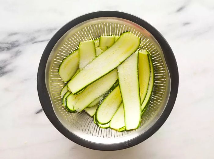 Zucchini slices draining in a colander