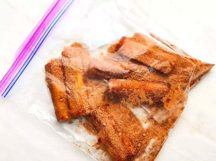 Pineapple wedges coated with brown sugar and cinnamon mixture inside a plastic bag.