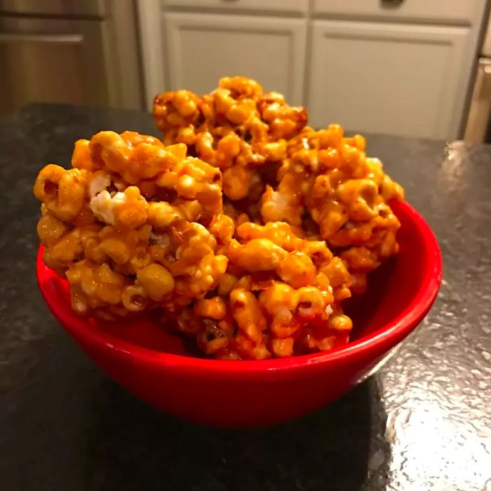 Caramel-coated popcorn balls neatly arranged in a red bowl