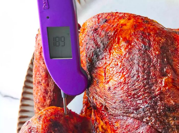 A digital thermometer checking the temperature of a fried turkey.