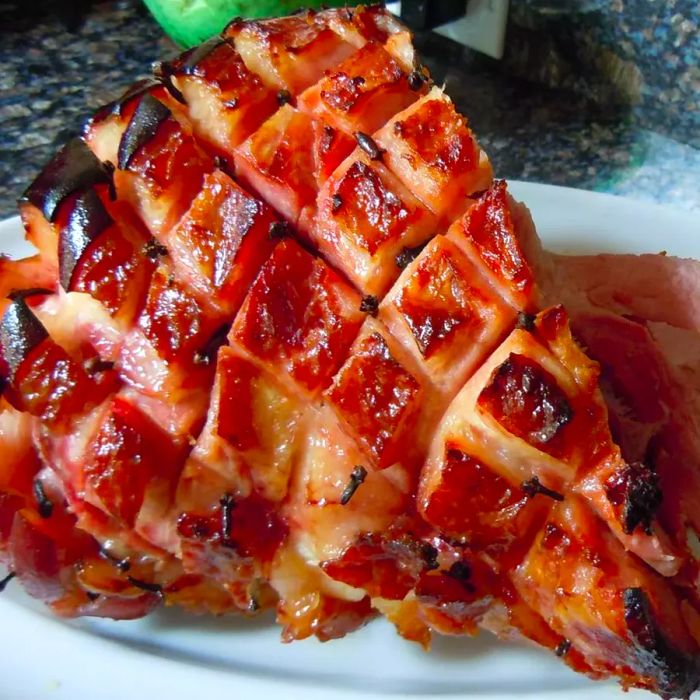 A beautifully baked glazed ham served on a white plate