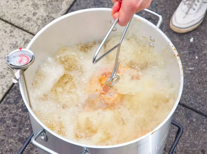 A whole turkey immersed in an outdoor deep fryer.