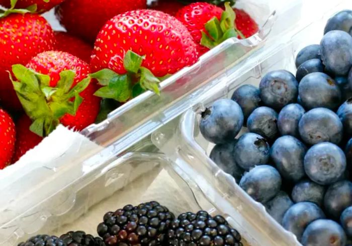 fresh strawberries, blueberries, and blackberries stored in plastic containers