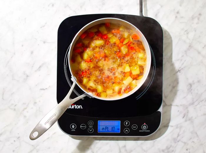 Carrots and potatoes simmering in beef broth until they become tender.