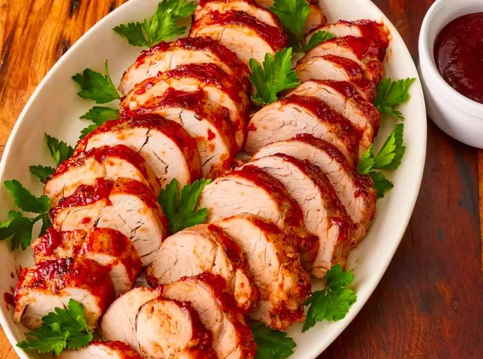 Sliced pork served on a platter, with the remaining barbecue sauce on the side.