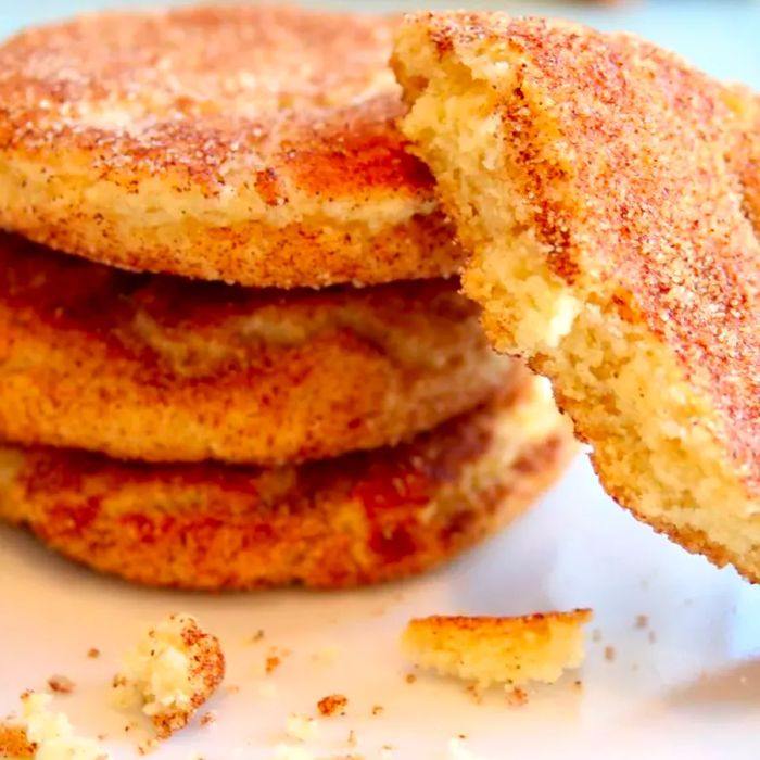 A side view of a stack of Mrs. Sigg's Snickerdoodles cookies, with one cookie broken open to show its soft interior