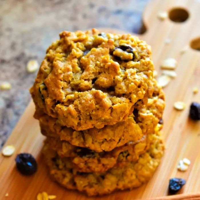 A stack of freshly baked Beth's Spicy Oatmeal Raisin Cookies arranged on a rustic wooden cutting board