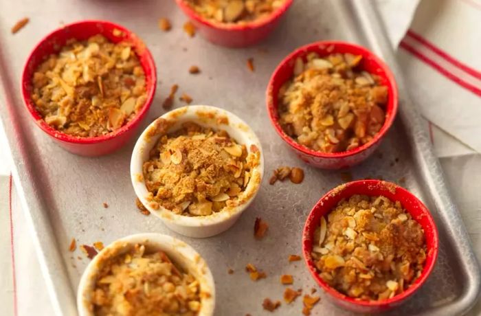 Fruit crisp baked in individual ramekins on a baking sheet