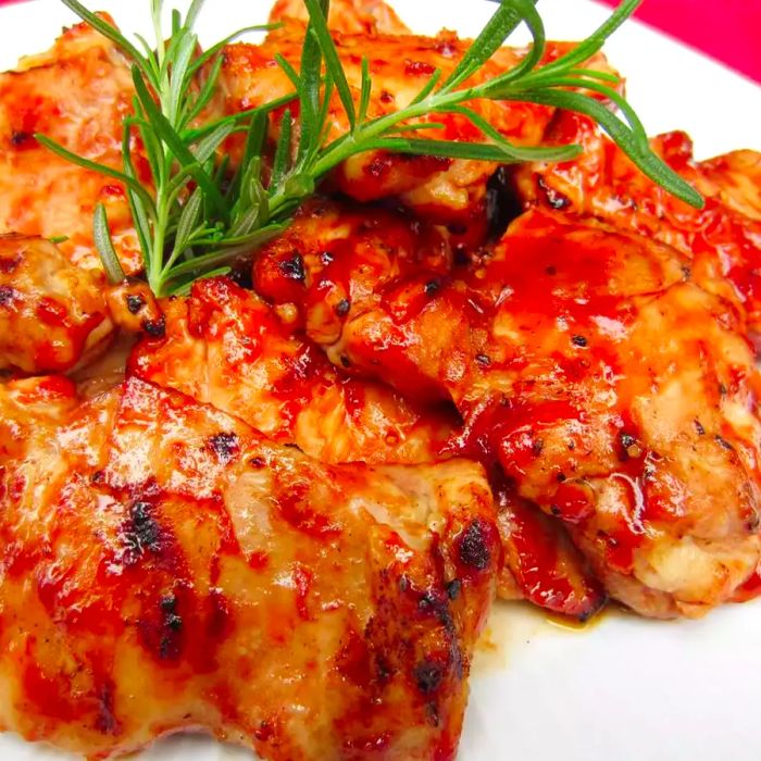 A close-up shot of BBQ chicken topped with fresh herbs on a white plate