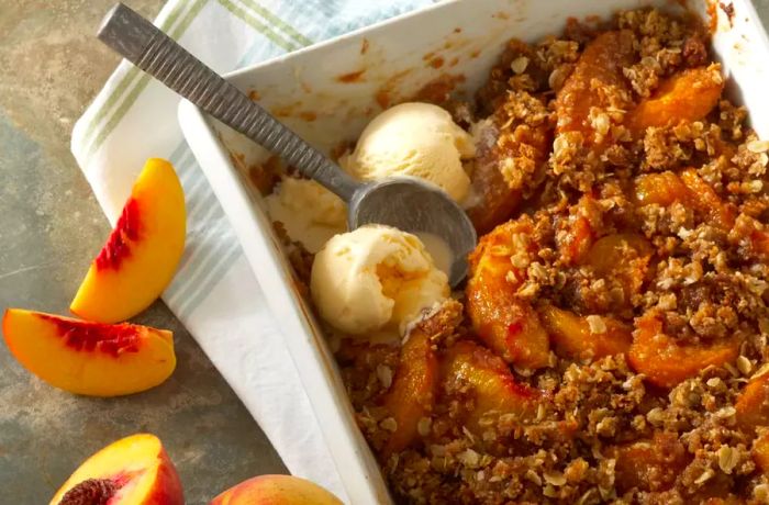 Close-up of homemade peach crisp with an oat topping in a white baking dish