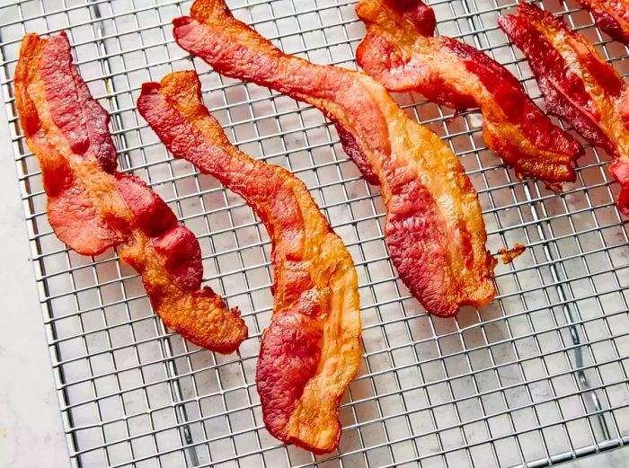 A close-up of crispy oven-baked bacon cooling on a rack