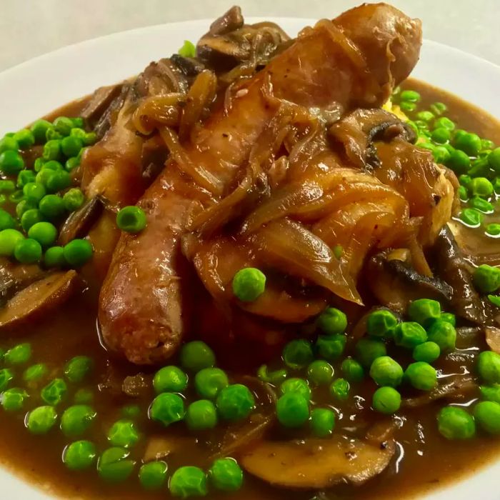 Classic Bangers and Mash with Onion Gravy served on a white plate