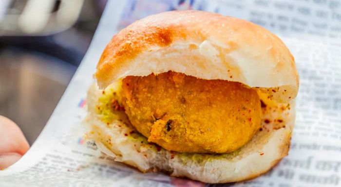 Vada pav: A golden, crispy deep-fried potato patty tucked inside a pillowy bun.