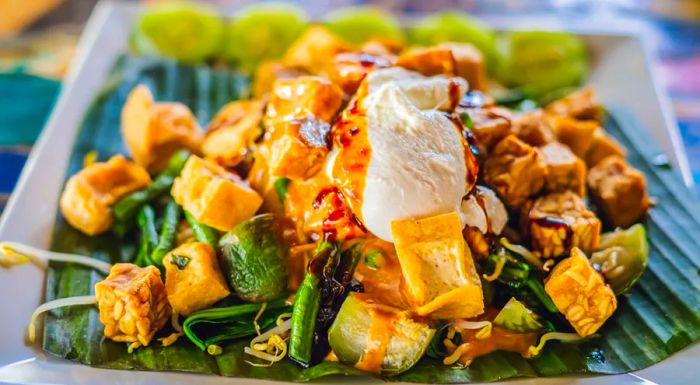 Gado gado is a vibrant medley of fresh vegetables dressed in a rich, peanut sauce.