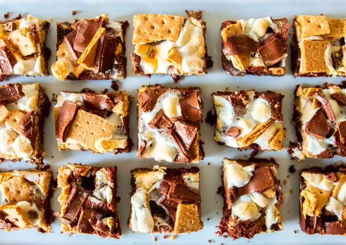 Overhead shot of s'more brownie squares topped with chocolate, graham crackers, and gooey marshmallows