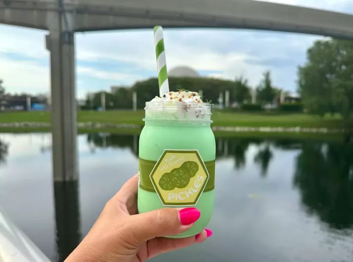 A hand holding a pickle milkshake at EPCOT