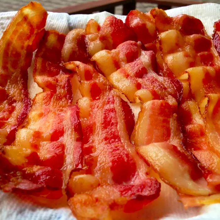 Baked bacon resting on paper towels to drain excess grease.