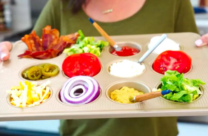 An assortment of condiments and toppings arranged in a muffin pan.