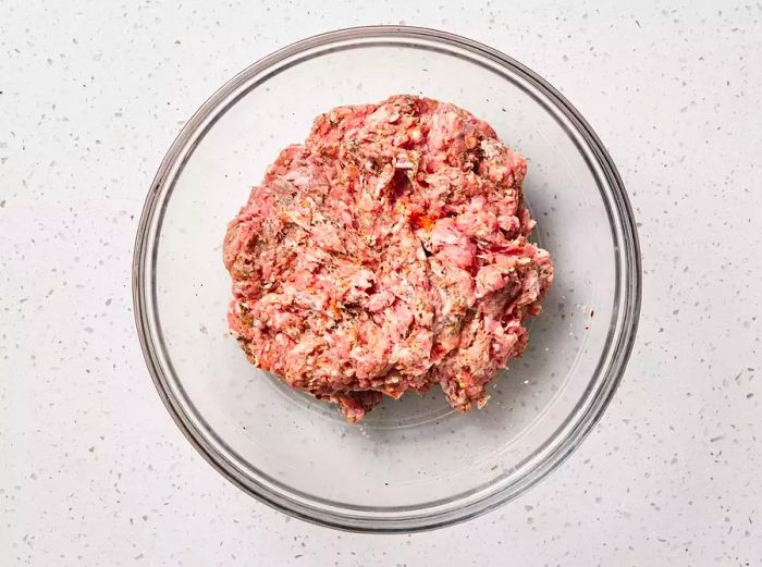 A glass bowl filled with seasoned ground pork