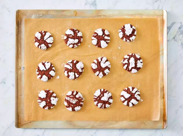 An overhead shot of freshly baked chocolate crinkle cookies cooling on the baking sheet, right out of the oven.