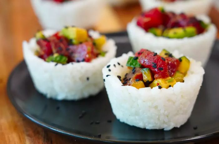 Three rice-filled cups topped with ahi tuna sushi, plated and ready to serve.