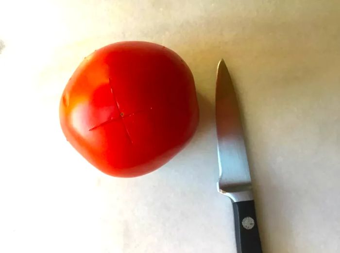 scored tomato with a knife